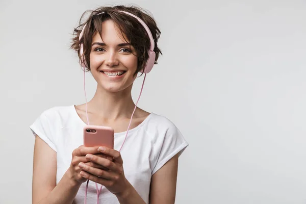 Imagen de mujer optimista en camiseta básica sosteniendo smartphone wh — Foto de Stock