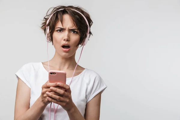 Imagem da mulher perplexa no smartphone básico t-shirt segurando enquanto — Fotografia de Stock