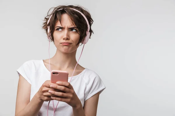 Imagen de mujer molesta en camiseta básica sosteniendo teléfono inteligente mientras l —  Fotos de Stock