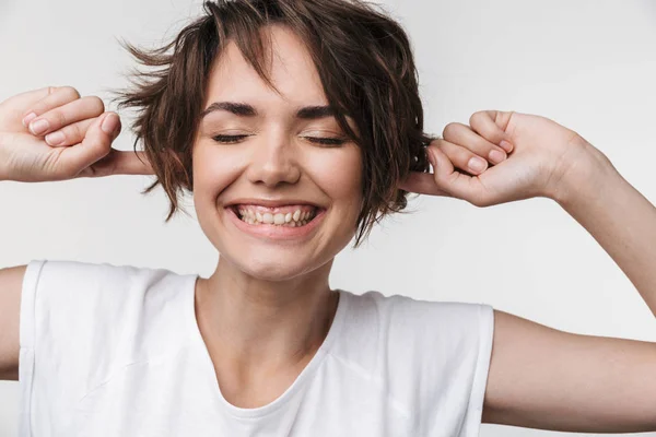 Joven bonita mujer feliz posando aislado sobre fondo blanco de la pared cubriendo las orejas . —  Fotos de Stock