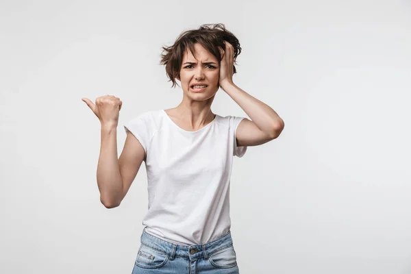 Young pretty displeased shocked woman posing isolated over white wall background pointing to copyspace. — ストック写真