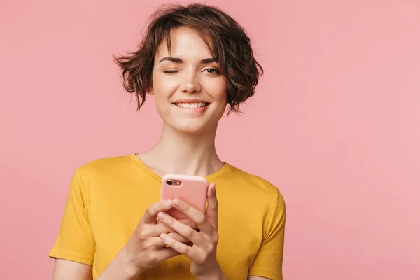 Glücklich junge schöne Frau posiert isoliert über rosa Wand Hintergrund mit Handy. — Stockfoto