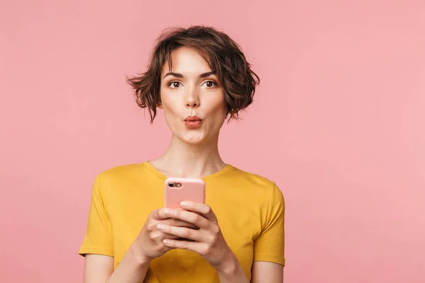 Σοκαρισμένος νεαρή όμορφη γυναίκα που παρουσιάζουν απομονωμένα πάνω από ροζ τοίχο φόντο χρησιμοποιώντας το κινητό τηλέφωνο. — Φωτογραφία Αρχείου