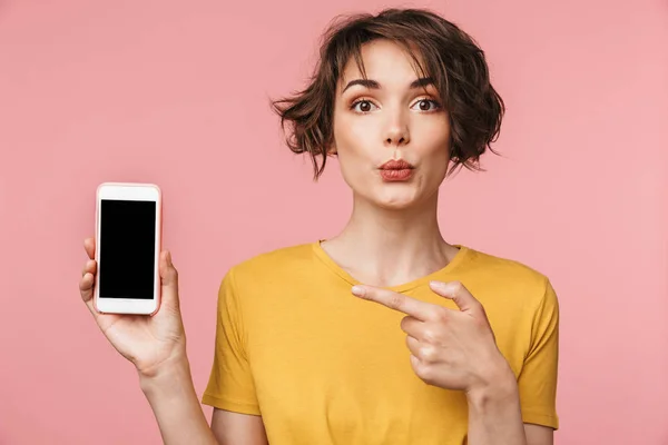 Joven mujer hermosa impactada posando aislada sobre fondo de pared rosa utilizando el teléfono móvil que muestra la pantalla . —  Fotos de Stock