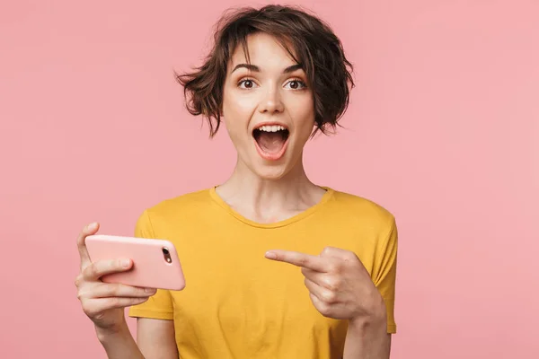 Choqué jeune belle femme posant isolé sur fond de mur rose jouer à des jeux par téléphone mobile . — Photo