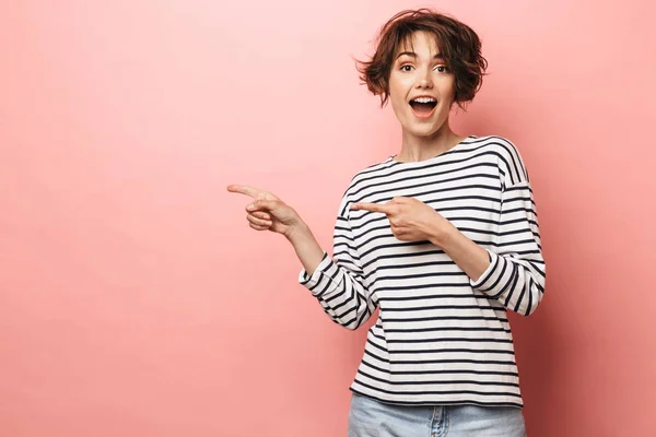 Emocionada sorprendida mujer hermosa posando aislada sobre fondo de pared rosa señalando . —  Fotos de Stock