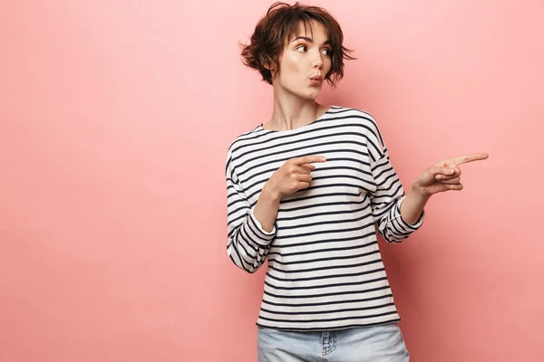 Emocionada sorprendida mujer hermosa posando aislada sobre fondo de pared rosa señalando . —  Fotos de Stock