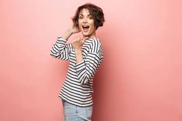 Feliz hermosa mujer posando aislada sobre fondo de pared rosa señalando . — Foto de Stock