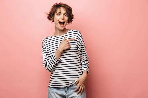 Emocionada sorprendida mujer hermosa posando aislada sobre fondo de pared rosa señalando . — Foto de Stock