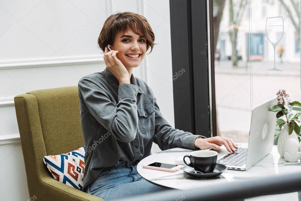 Attractive young woman sitting at the cafe table indoors