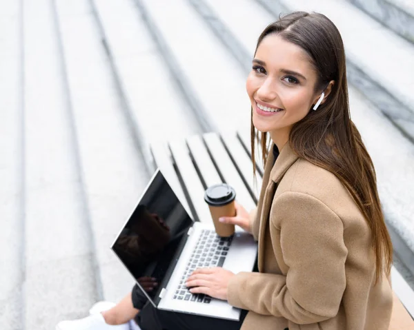 Mooie jonge vrouw draagt herfst vacht met behulp van laptop — Stockfoto