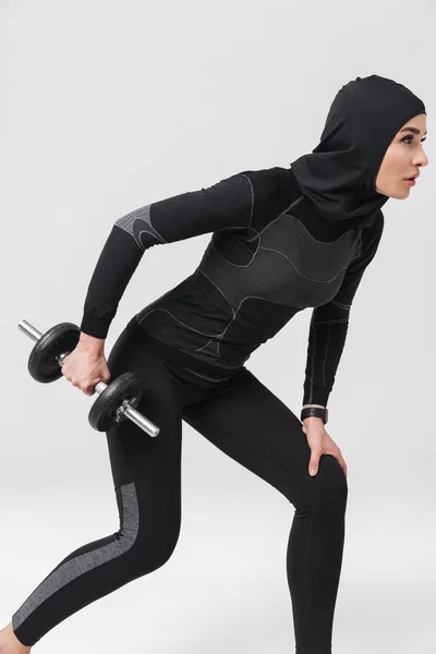 Kadın fitness müslümanı, beyaz arka planda yalnız poz veriyor. Dambılla egzersiz yapıyor.. — Stok fotoğraf