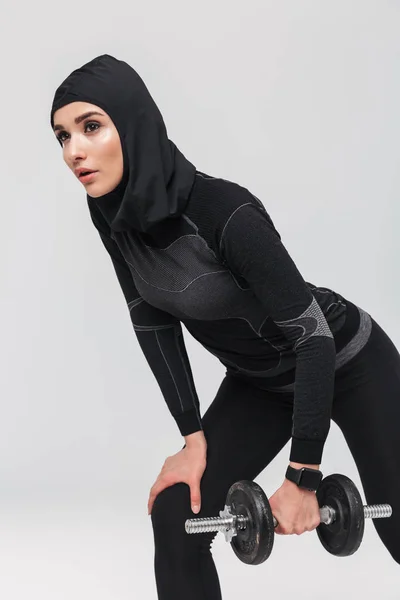 Женщина фитнес-мусульманин позирует изолированные на белом фоне стены сделать упражнения с гантели . — стоковое фото