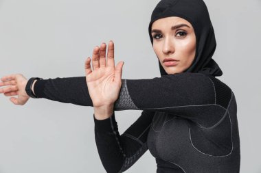 Genç kadın fitness müslümanları esneme egzersizlerini beyaz duvar arka planında izole ediyor..