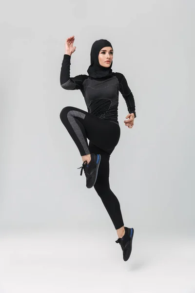 Kobieta fitness muzułmanin pozowanie bieganie skoków izolowane na białym tle ściany. — Zdjęcie stockowe