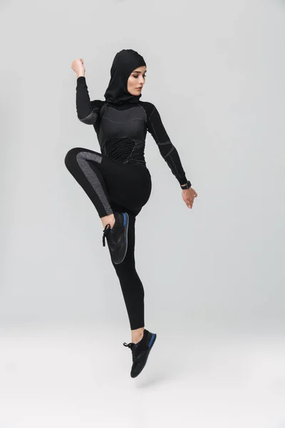 Женщина фитнес-мусульманин позирует бег прыжки изолированы на белом фоне стены . — стоковое фото