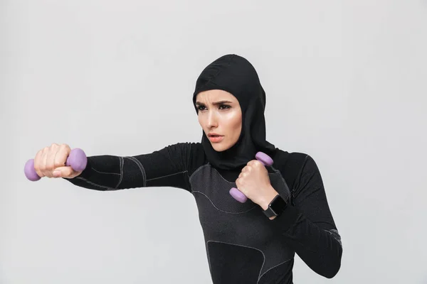 Молодая женщина фитнес-мусульманин делать упражнения с гантелями изолированы на белом фоне стены . — стоковое фото