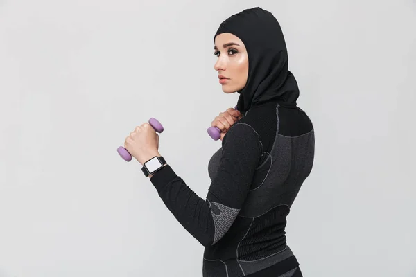 Jovem mulher fitness muçulmano fazer exercícios com halteres isolados sobre fundo da parede branca . — Fotografia de Stock