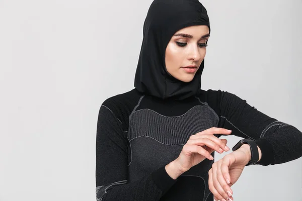 Młoda kobieta fitness muzułmanin za pomocą zegara odizolowane na białym tle ściany. — Zdjęcie stockowe