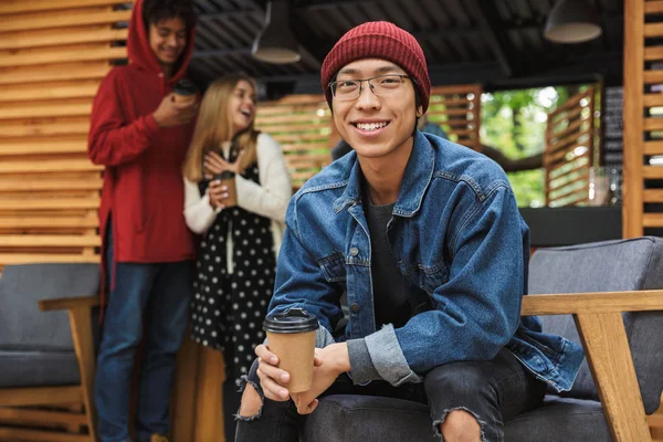 Leende asiatiska tonåring sitter utomhus — Stockfoto