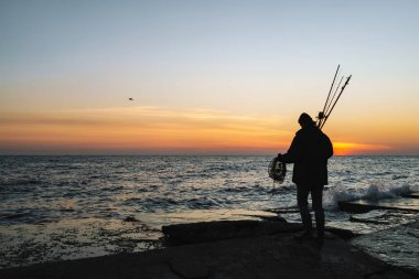 Ceket giyen adam balıkçı silueti, çubuk tutan