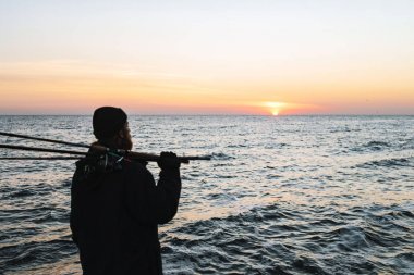 Ceket giyen adam balıkçı silueti, çubuk tutan