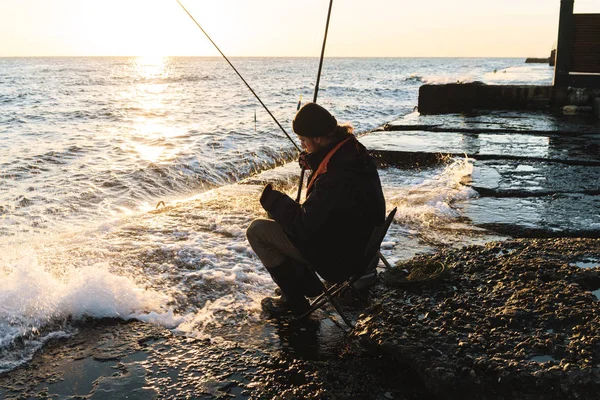 Красивый молодой человек рыбак в пальто и шляпе на берегу моря . — стоковое фото