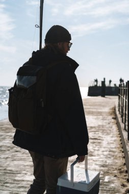 Ceket giyen adam balıkçı silueti, çubuk tutan