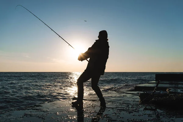 Sylwetka mężczyzny rybaka noszący płaszcz, pręt trzymania — Zdjęcie stockowe