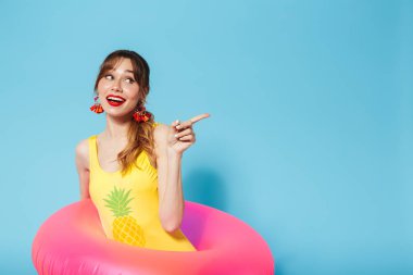 Mayo giymiş genç bir kız şişirilebilir halkada mavi arka planda yalnız poz veriyor..