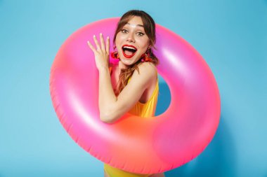 Mayo giymiş genç bir kız şişirilebilir halkada mavi arka planda yalnız poz veriyor..