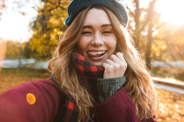 Beautiful happy young pretty woman walking outdoors in autumn spring park take a selfie by camera. — Stock Photo, Image