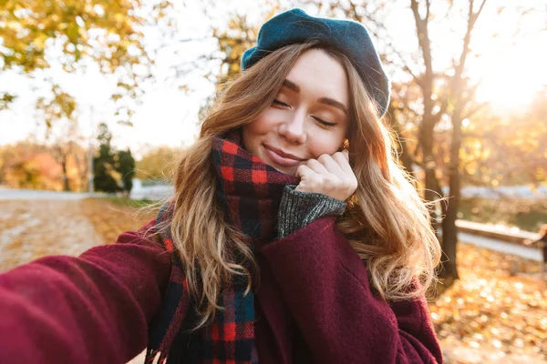 Hermosa feliz joven bonita mujer caminando al aire libre en otoño primavera parque tomar un selfie por cámara . — Foto de Stock