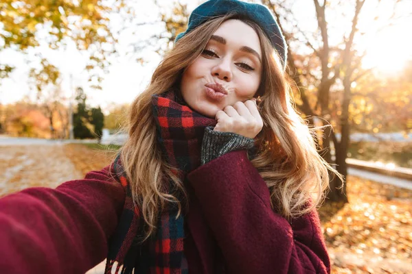 Beautiful happy young pretty woman walking outdoors in autumn spring park take a selfie by camera. — Stock Photo, Image