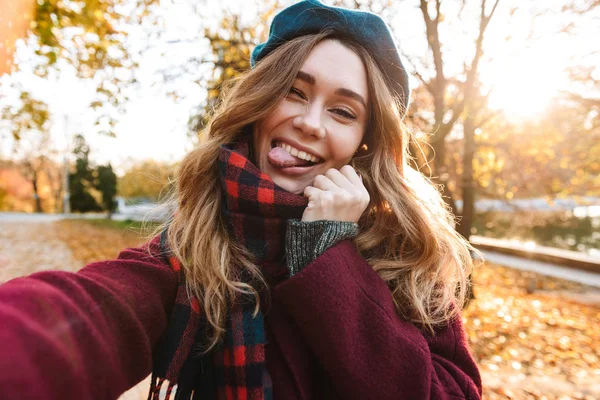 Hermosa feliz joven bonita mujer caminando al aire libre en otoño primavera parque tomar un selfie por cámara . — Foto de Stock