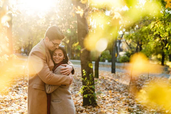 Bild eines jungen glücklichen Paares, das im Herbstpark lächelt und sich umarmt — Stockfoto