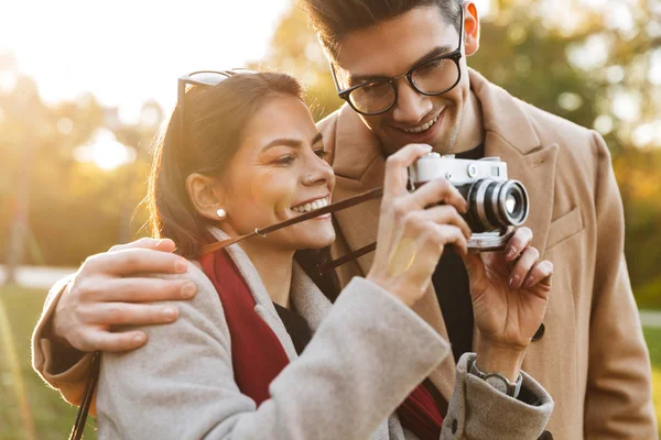 Retrato de casal sorridente tirando foto na câmera retro enquanto caminhava no parque de outono — Fotografia de Stock