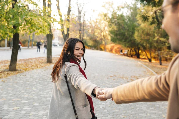 Portret van jonge vreugdevolle paar glimlachen en handen vasthouden tijdens het wandelen in het herfst Park — Stockfoto
