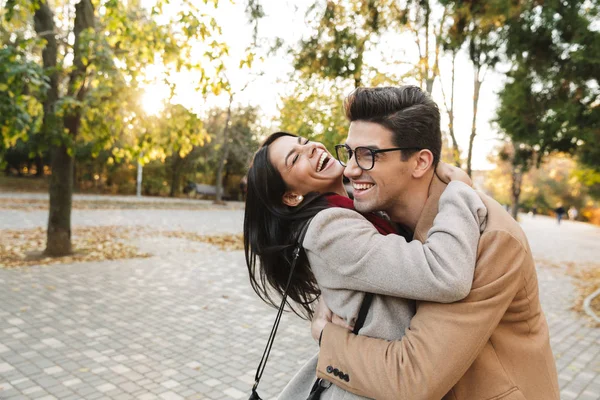 Portrait of happy joyful couple laughing and hugging each other while walking in autumn park — Stock Photo, Image