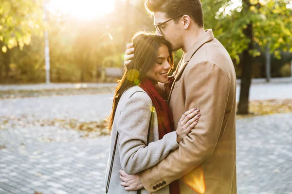 Retrato de pareja romántica feliz sonriendo y abrazándose mientras caminan en el parque de otoño — Foto de Stock