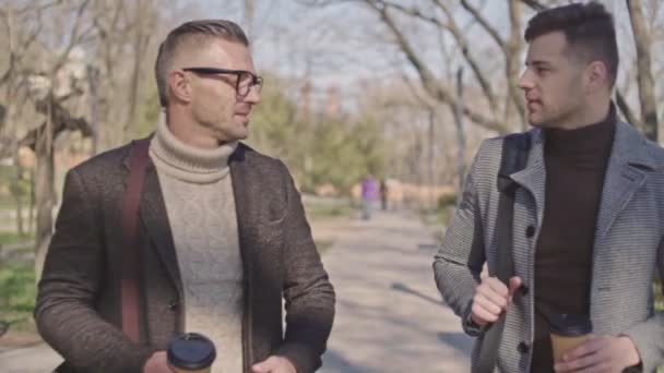 Два Стильных Взрослых Мужчины Чашками Кофе Говорят Время Прогулки Парке — стоковое видео