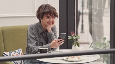 Kafede oturan akıllı telefon bir video görüşmesi olan Pretty genç kadın