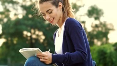 Mutlu dalgın esmer kadın çim üzerinde oturan ve parkta dizüstü bir şey yazma