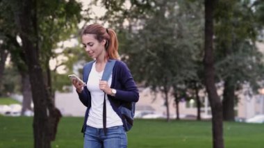 Parkta akıllı telefon kullanarak sırt çantası ile Mutlu esmer kadın