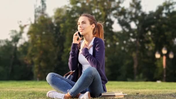 Mujer Morena Feliz Sentado Hierba Hablando Por Teléfono Inteligente Parque — Vídeos de Stock