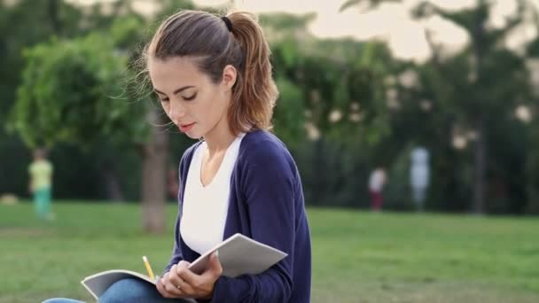 Mulher Morena Calma Sentada Grama Escrevendo Algo Notebook Parque — Vídeo de Stock