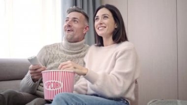 Mutlu güzel çift birlikte tv izlerken ve evde patlamış mısır yeme