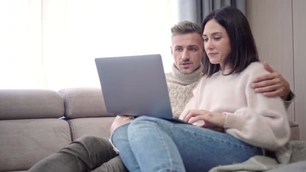 Feliz Pareja Encantadora Usando Ordenador Portátil Mientras Sienta Sofá Casa — Vídeos de Stock