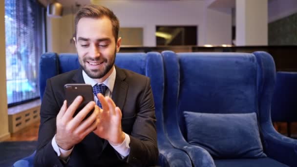 Lachende Bebaarde Man Met Een Smartphone Terwijl Een Fauteuil Het — Stockvideo
