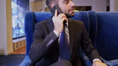 Kafede koltukta otururken akıllı telefon ile konuşan mutlu sakallı iş adamı